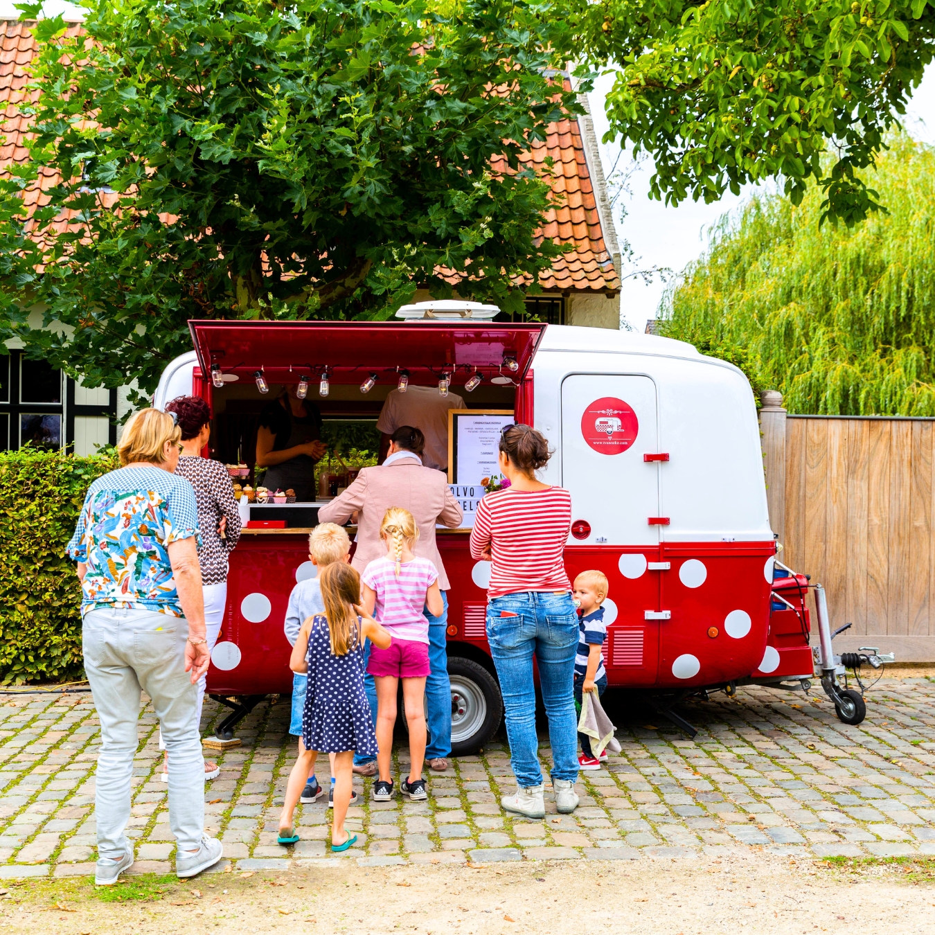 Werknemers en hun kinderen schuiven aan bij een foodtruck vol cupcakes